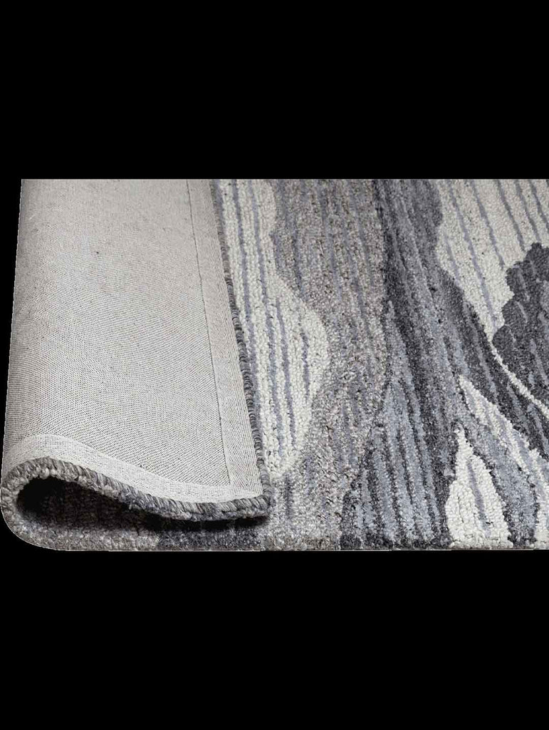 The Tribe Home 100% wool Hendrix rug in colours grey, ivory and blue, shown with the end rolled up to reveal the underneath