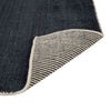 Close up of the weave of a dark blue wool blend floor rug with corner folded to reveal underneath