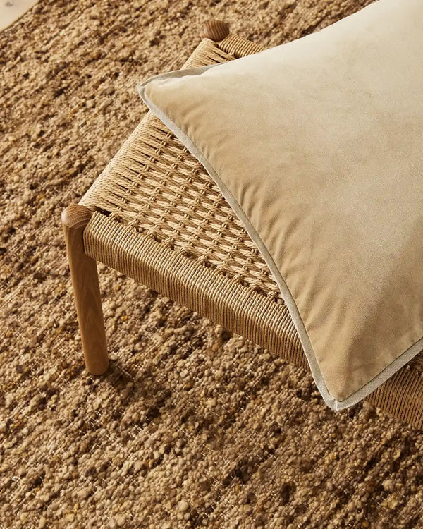 Weave Home Francesca velvet-look cushion in a light, mustard yellow sitting on a woven stool