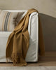 Weave Home wool throw blanket in colour 'camel' - a light brown, draped over a couch