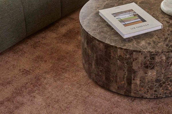 A warm brown wool blend floor rug seen in a contemporary home under a stylish coffee table