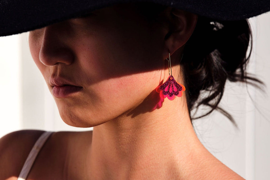 A stylish woman wearing pink Mumbai dangle earrings by Hagen + Co