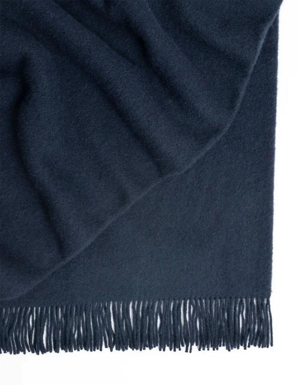 An indigo-blue coloured NZ lambswool throw blanket with fringe 