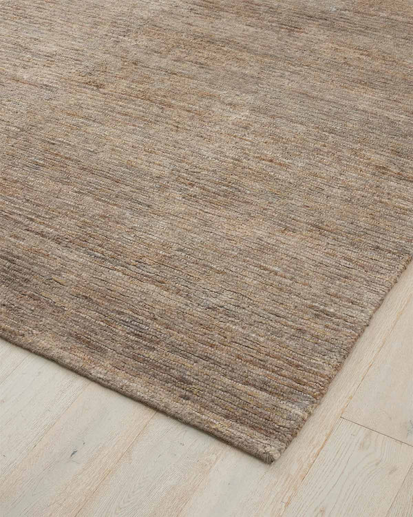 A taupe floor rug in hand knotted jute, with a high texture of alternating cut and looped pile. 