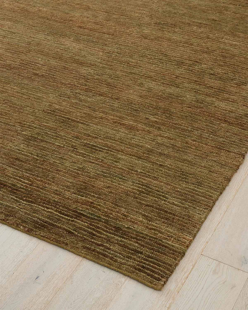 A natural jute olive green toned floor rug with textured loop and cut pile. 