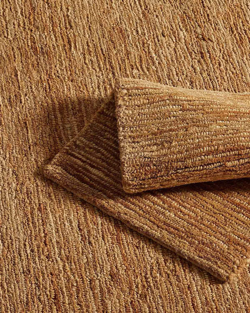 A natural jute mat and a floor rug in natural brown tones with loop and cut weaving. 