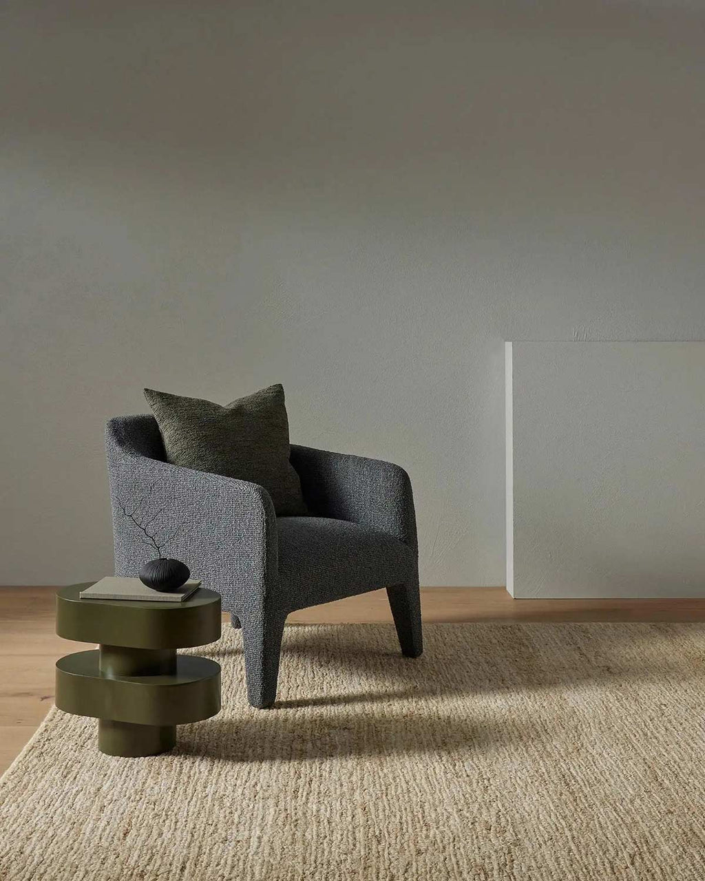 A chair and sculptural table atop a highly textured natural jute fibre handwoven cream toned floor rug. 