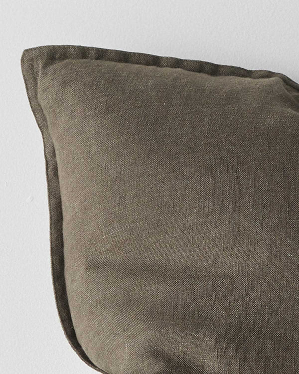 A corner of a deep warm olive green toned cushion in European linen with a flanged edge. 