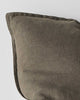A corner of a deep warm olive green toned cushion in European linen with a flanged edge. 