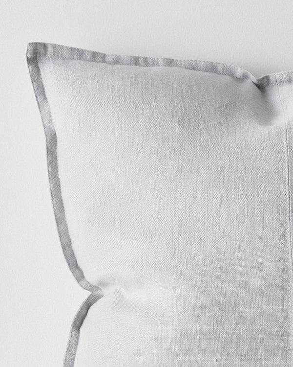 A close up of the corner of a soft light grey cushion with a flanged edge, made with European linen.