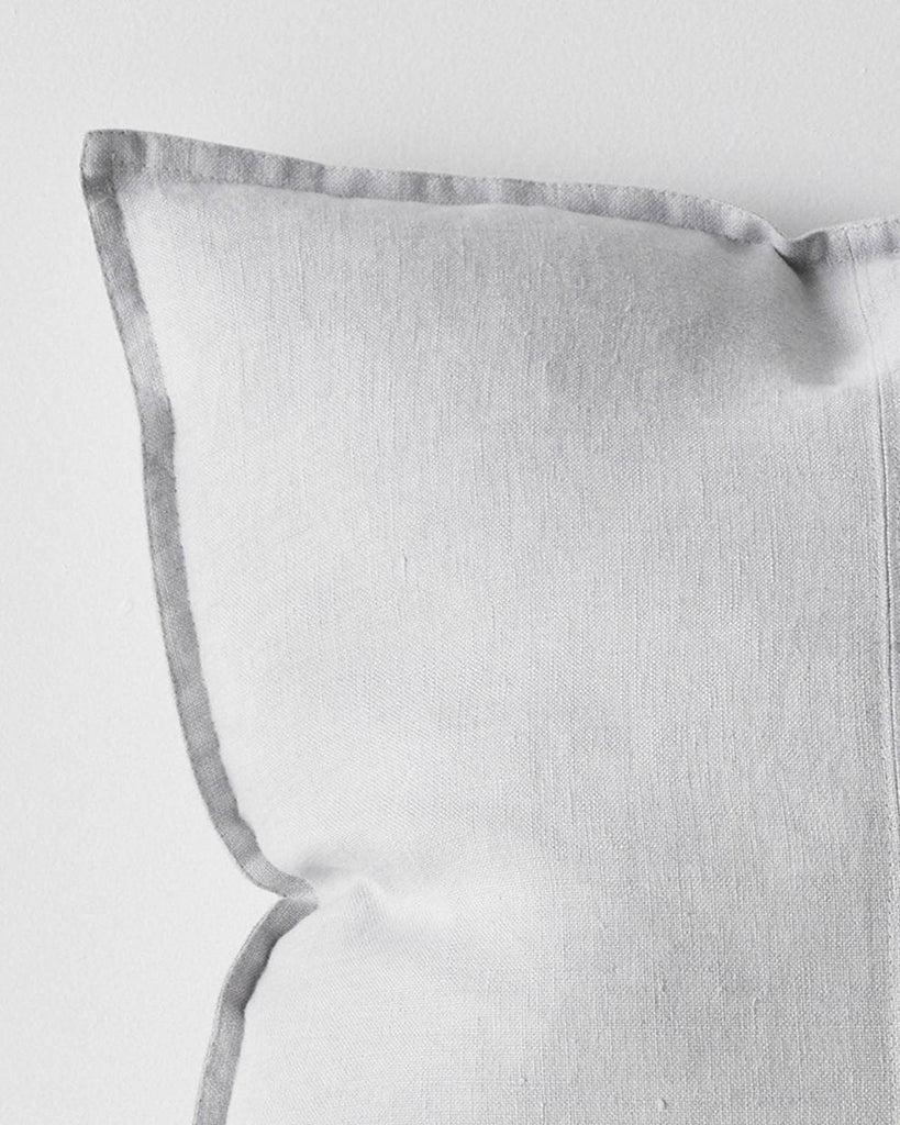 A close up of the corner of a soft light grey cushion with a flanged edge, made with European linen.