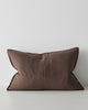 A lumbar cushion in a warm deep brown shade with a seam down the middle and flanged edges. 