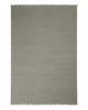A full image of a handwoven linen floor rug in a soft grey green tone with fringe edging. 