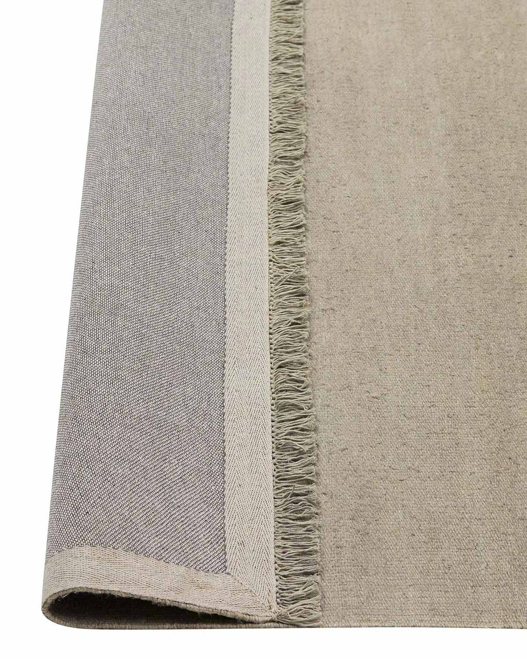 A handmade linen floor rug in cool taupe with fringed edges— the corner is flipped up to show the durable cotton underside. 