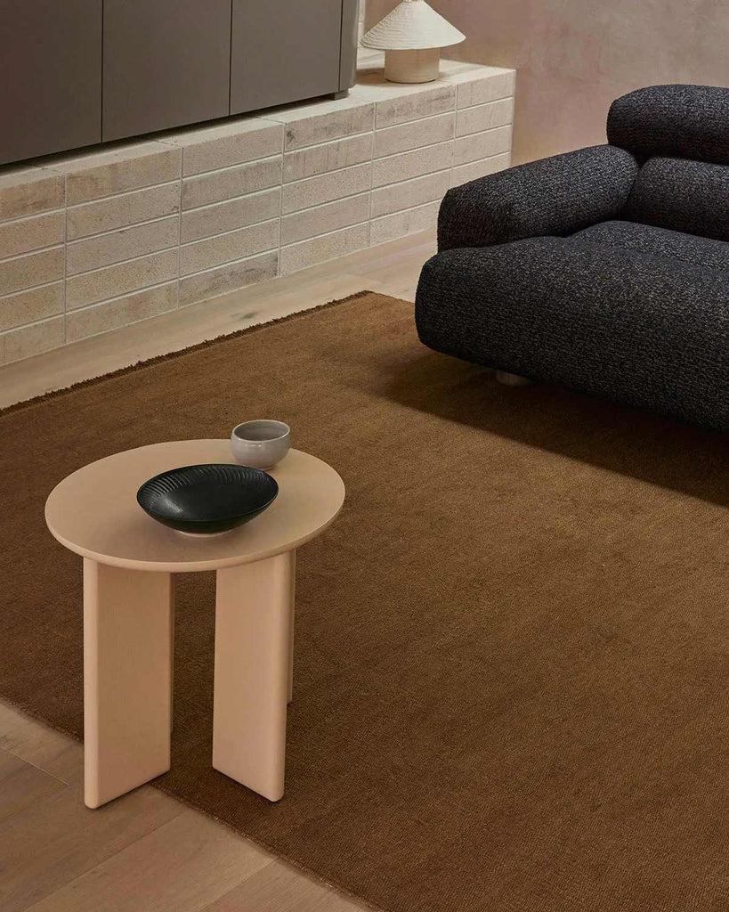 A sitting room with a modern designer coffee table and a warm mid-toned brown floor rug made with 100% linen. 