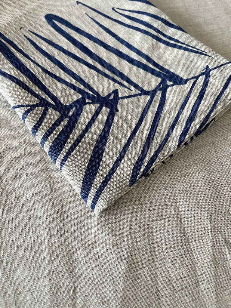 Folded handprinted linen teatowel 'Leaf Navy Blue' by Smitten Textile Designs, on natural oat linen