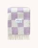 A folded NZ wool throw with a checkerboard pattern, alternating squares of lilac and cream, by Maison Deux