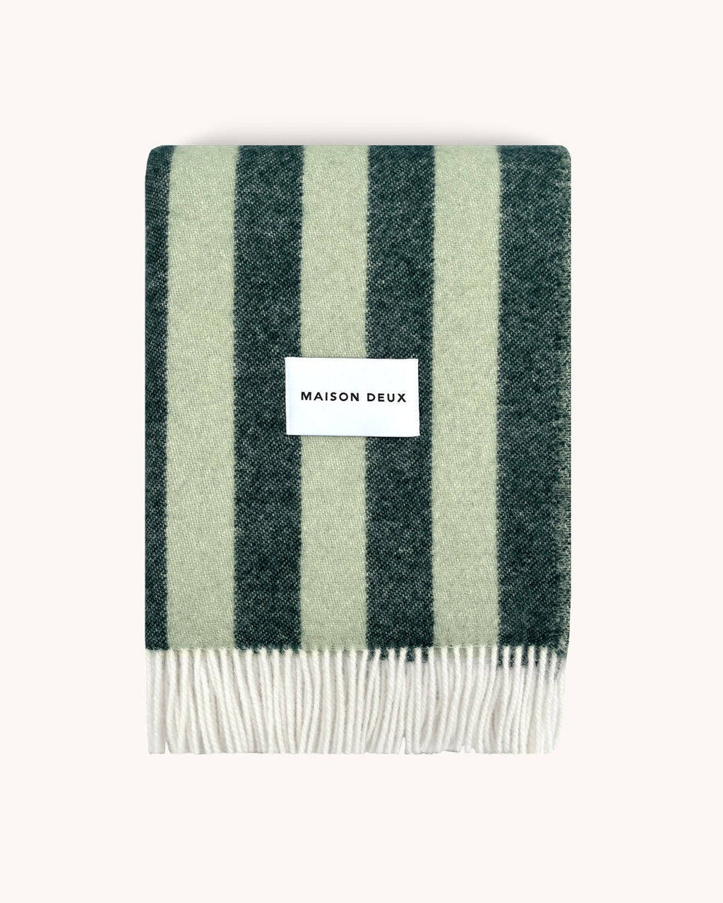 A folded woolen throw blanket with a striped pattern, alternating dark and light green, by Maison Deux