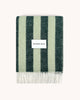 A folded woolen throw blanket with a striped pattern, alternating dark and light green, by Maison Deux