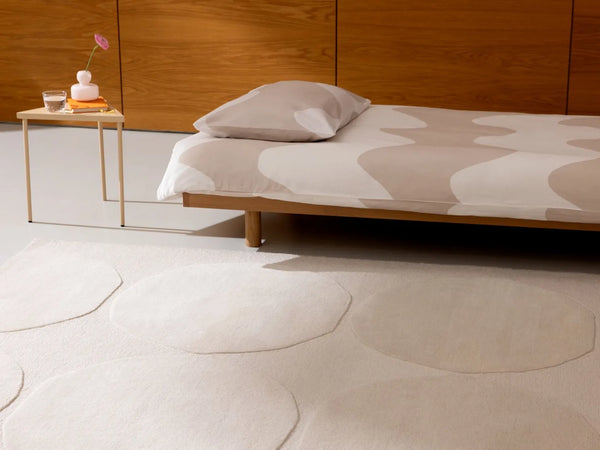 The Marimekko Isot Kivet wool floor rug in a calming natural white colour, seen in a modern bedroom