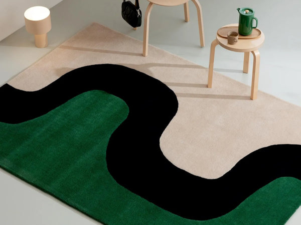 The Marimekko Seireeni green floor rug featuring an organic curve design, seen in a modern room