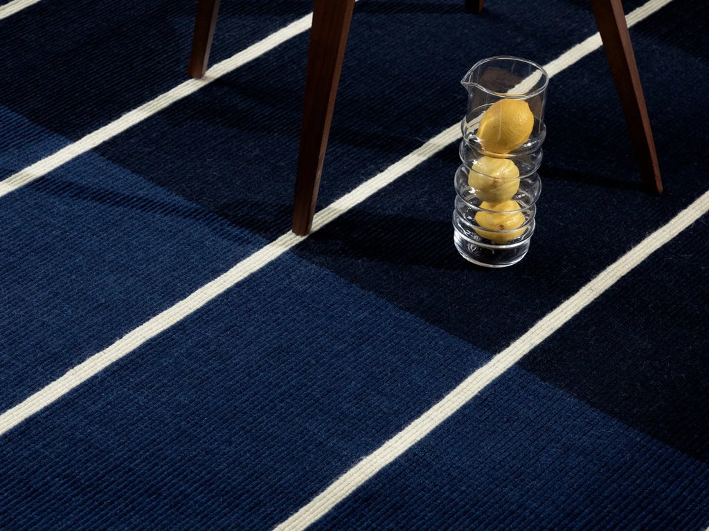 The Marimekko Tiibet floor rug, made from recycled PeT yarns, in deep blue colour, seen under a chair leg