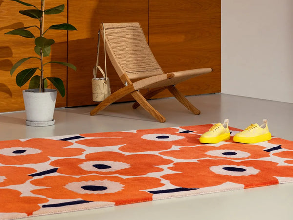 The Marimekko Unikko wool floor rug in orange-red, seen in a modern room