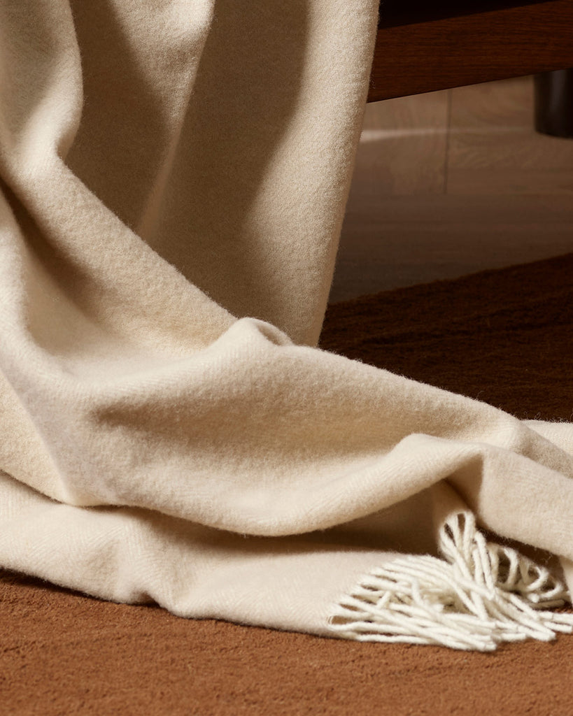 A detailed view of the oyster off-white throw blanket with white twist edging in 100% merino wool. 