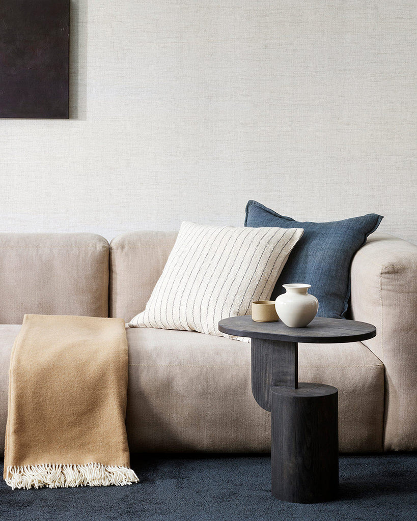 A couch with designer cushions and a 100% merino wool throw blanket in a beautiful warm soft sand tone. 