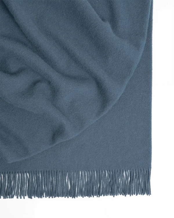 A blue-grey NZ lambswool throw blanket with fringe, by Weave Home