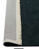 A deep blue 100% wool floor rug with off-white fringed edges, the corner of which is flipped up to show the cotton backing. 