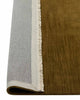 A detailed view of the linear weave of a 100% wool floor rug in deep yellow green brown tones, with a cream fringed edge. The corner is flipped up to show the sturdy cotton backing. 