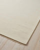 A corner of a soft cream ivory floor rug in 100% NZ wool with matching fringed edges. 