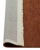 A red brown floor rug with cream toned fringed edges. The corner is flipped up to show the underside. 