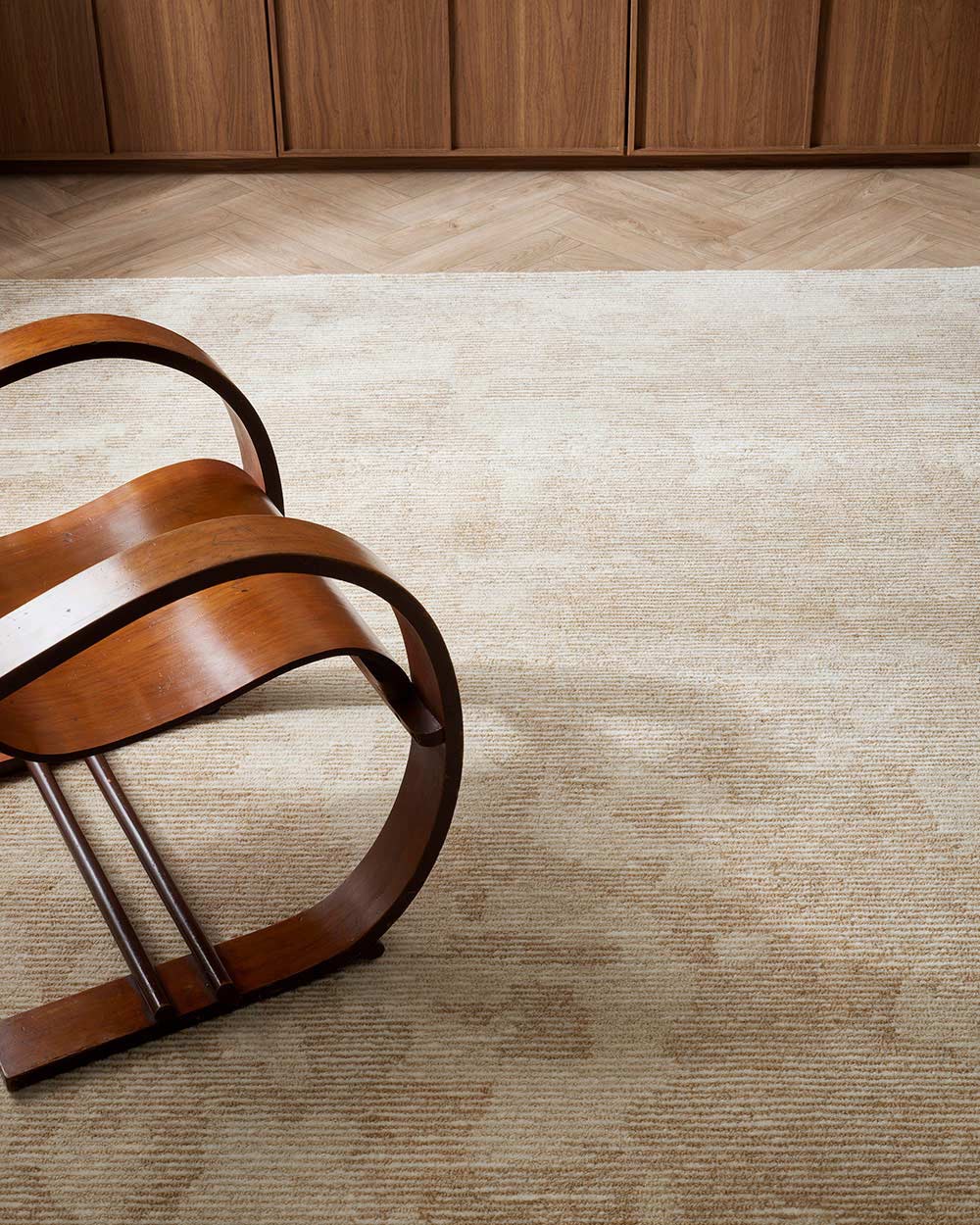 A designer chair on top of a beautiful New Zealand wool floor rug in shades of neutral cream and beige, with texturality through the cut and loop piling. 
