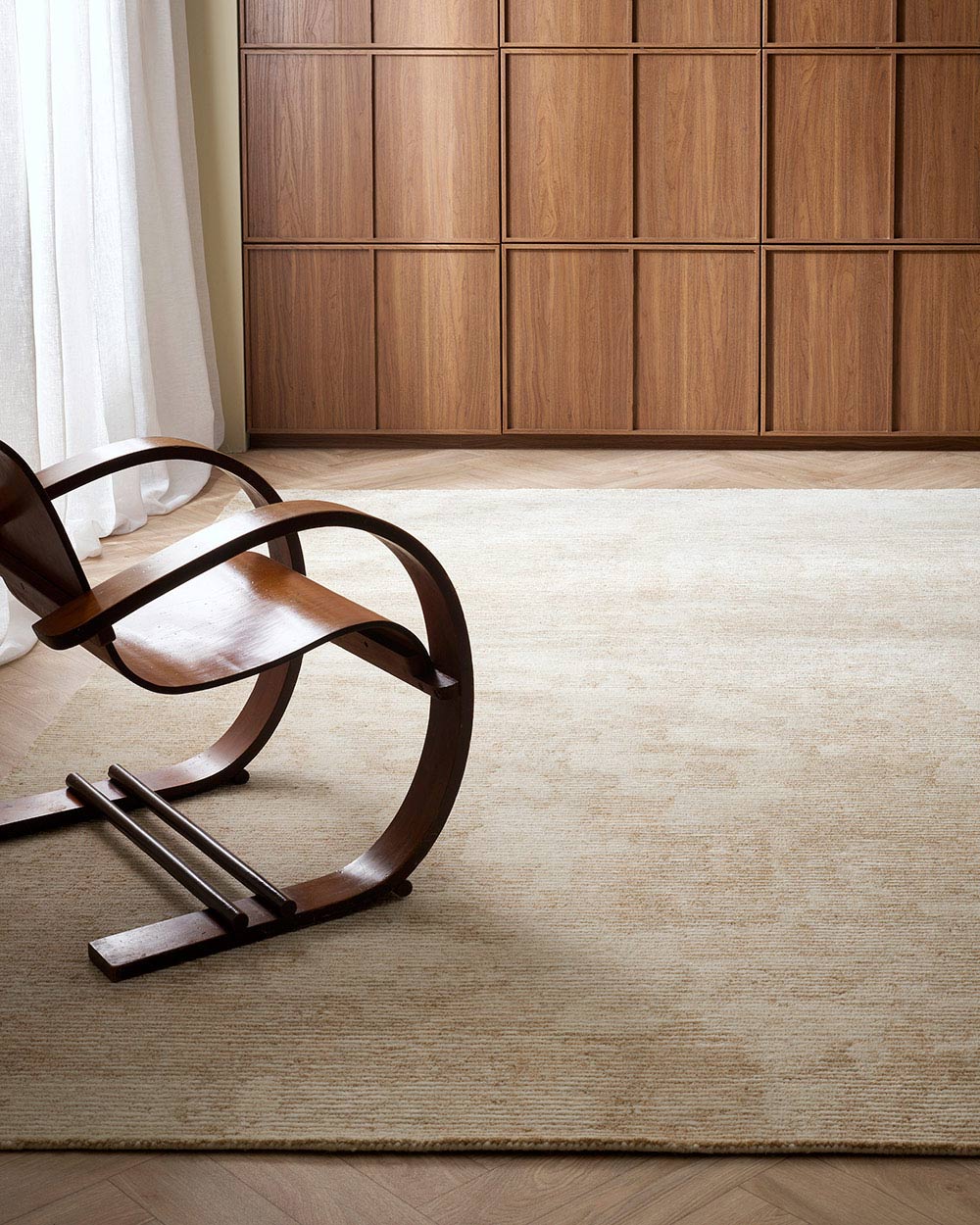 A simple living room with a cream toned floor rug, which has very subtle patterning. 