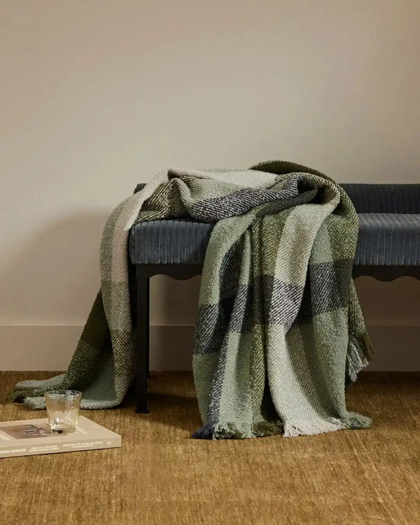 A green plaid boucle NZ-made throw blanket, by Weave Home nz. draped on a stool