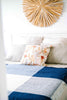 NZ wool throw blanket in blue and white check by Ruanui Station, seen on a bed in a white modern bedroom