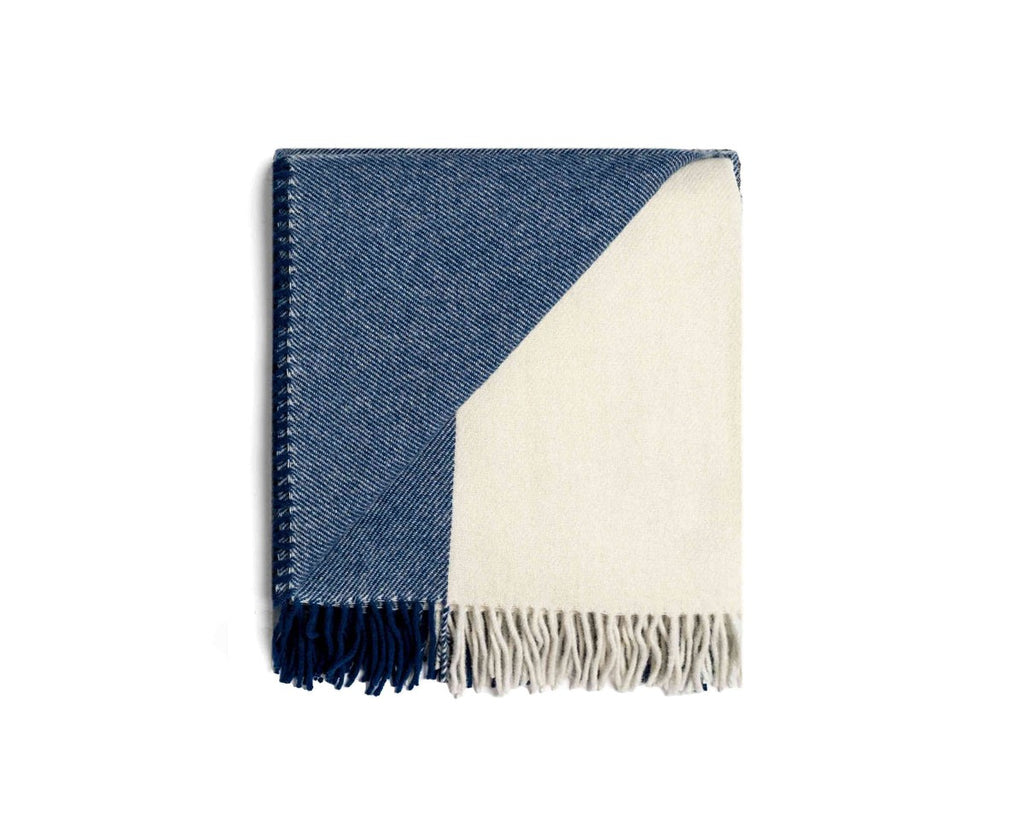 NZ wool throw blanket in blue nad white stripe, by Ruanui Station, seen folded with a corner lifted to reveal a creamy white