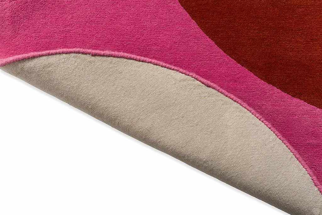 The red and pink round spot flower floor rug by Orla Kiely seen with edge folded to reveal underneath