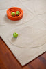 Orla Kiely designer floor rug 'Solid Stem Ecru' seen close up from above with props