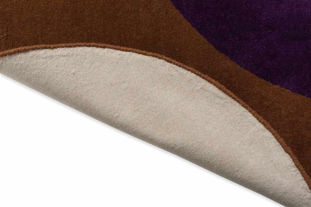 The Orla Kiely round Spot Flower 100% wool rug, in colour chestnut brown and violet, close up with edge folded to reveal underneath