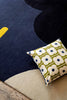 The Orla Kiely Geo Flower floor rug, in colour denim blue, seen from above with a cushion on it