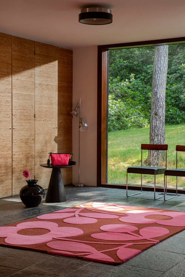 The Orla Kiely Sprig Stem floor rug in colour 'paprika' pink and red, seen in a modern living room