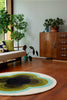The Orla Kiely round sunflower rug in beautiful olive green shades, seen in a retro-styled living room