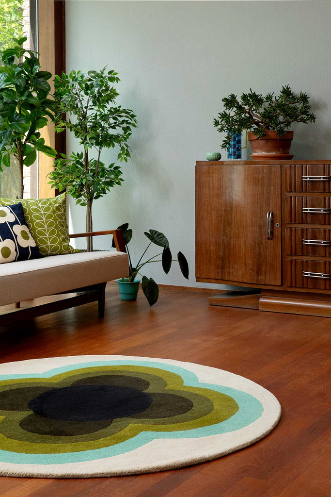 The Orla Kiely round sunflower rug in beautiful olive green shades, seen in a retro-styled living room