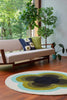 The Orla Kiely round sunflower rug in beautiful olive green shades, seen in a retro-styled living room