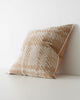 A side view of a patterned cushion with an oversized check print, in shades of muted orange and white. 