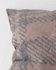 A close up image of a textural check patterned cushion in muted pink and purple tones. 