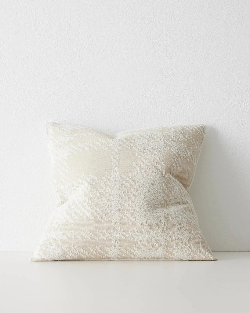 A textural cushion with an oversize check pattern in shades of cream and off-white. 